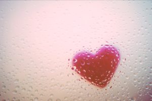 Heart behind glass with water drops
