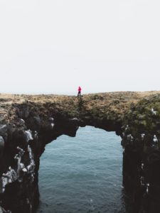 person crossing a natural arch over water