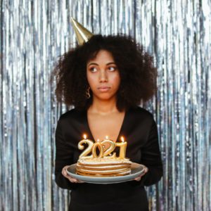 sad woman holding a cake with 2021 on top