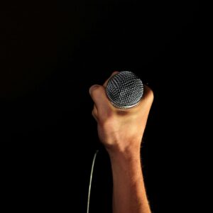 a hand holding a microphone against a black background, implying the weight of media silence